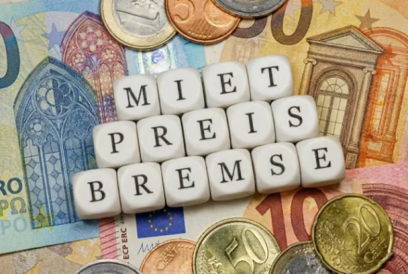 Würfel, auf denen das Wort Mietpreisbremse zusammengelegt wurde, auf Euro-Banknoten