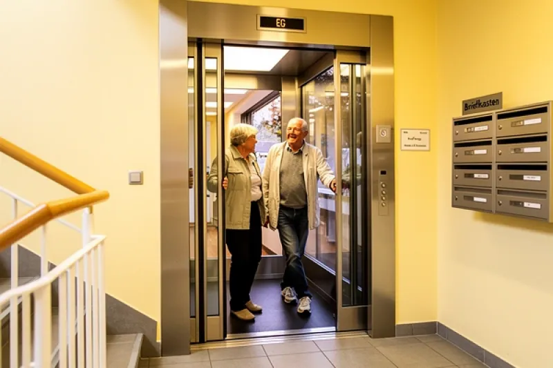älteres Ehepaar steigt in einen Aufzug eines Mehrfamilienhauses