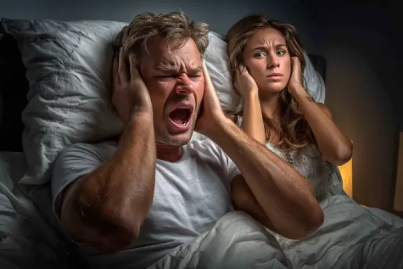 Mieterehepaar liegen im Bett und halten sich die Ohren zu