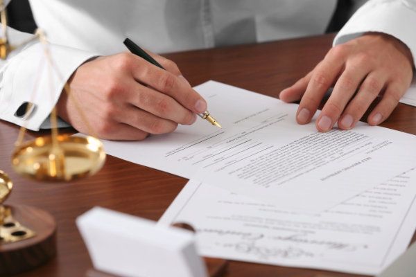 "HĂ€nde einer Person, die ein Dokument mit einem FĂŒller unterschreibt