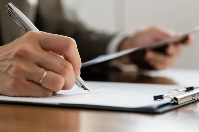Symbolbild: eine männliche Person unterschreibt ein Dokument