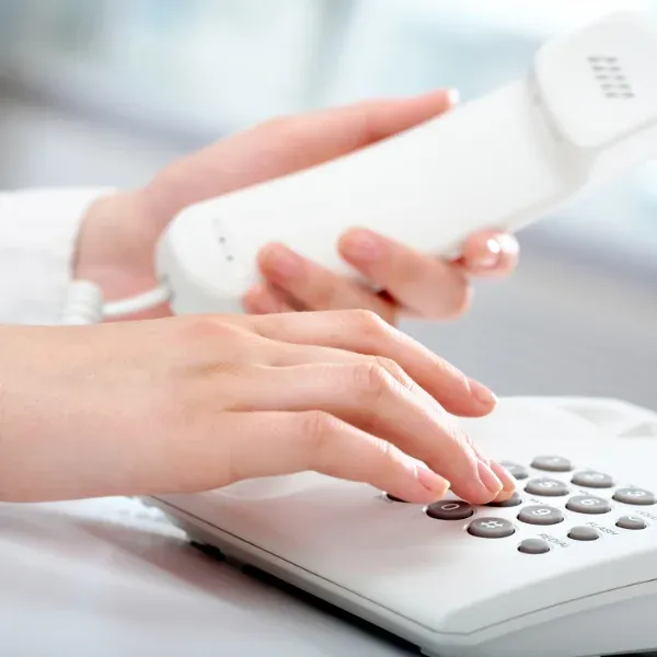 Frauenhände bedienen ein Festnetztelefon